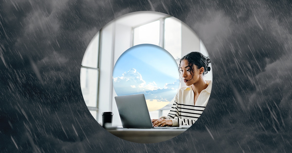 Professional working on laptop unaffected by storm, symbolizing business continuity and resilience