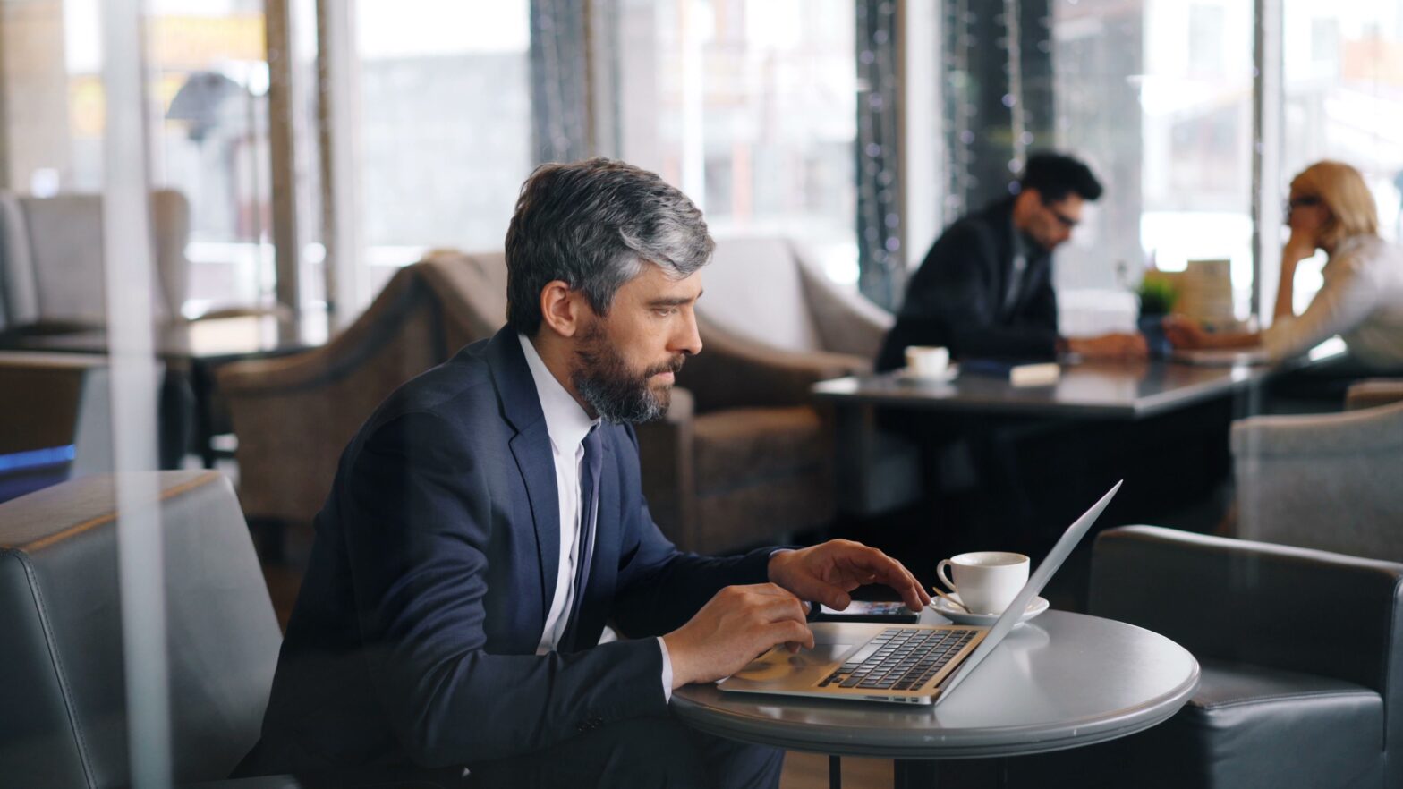 Employees working in an office while a computer displays a cybersecurity alert, illustrating the growing threat of AI phishing emails and business email compromise.