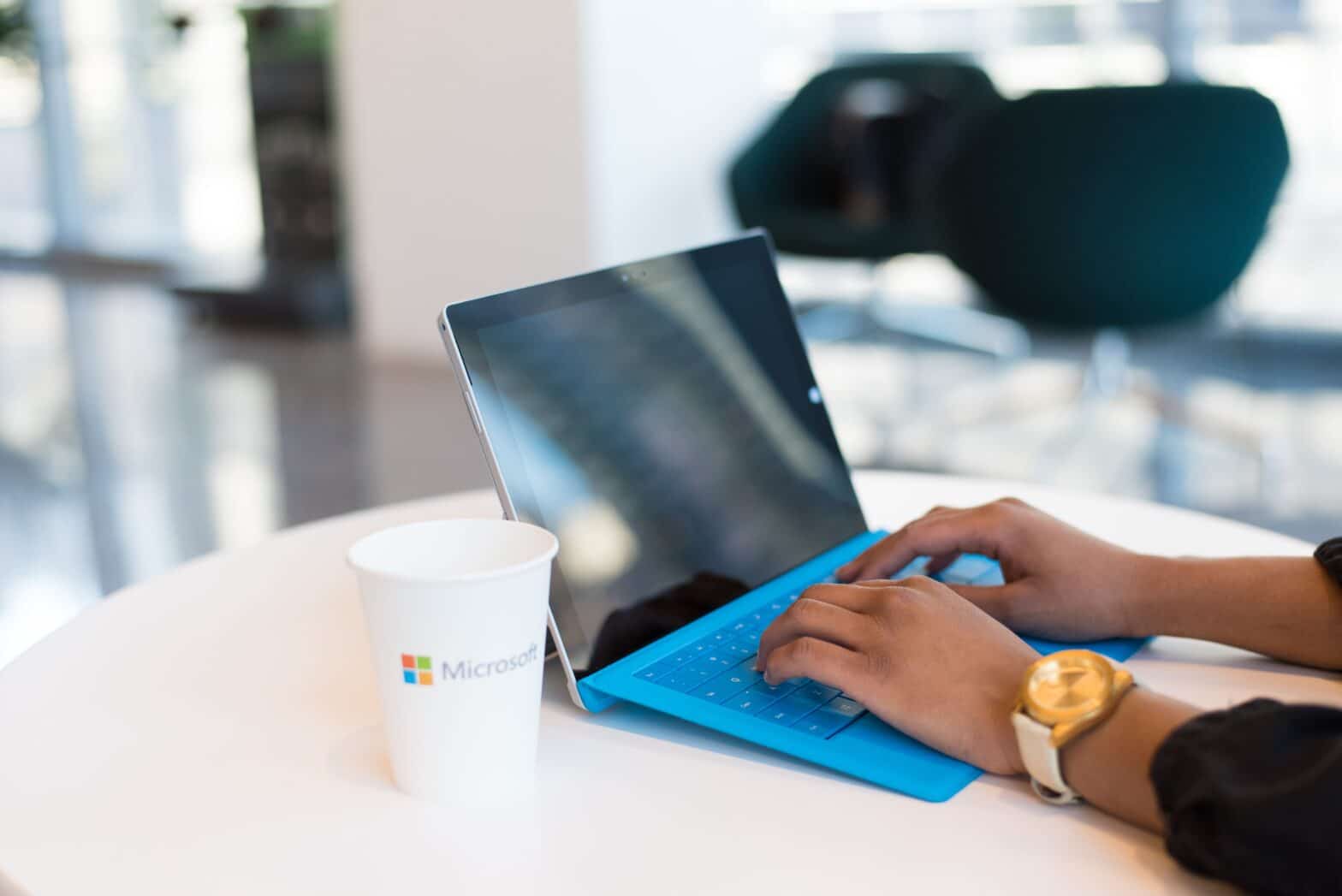 Person using a Microsoft Surface laptop with Microsoft 365 in a modern office, representing productivity tips for Outlook, Excel, Word, Teams and AI.