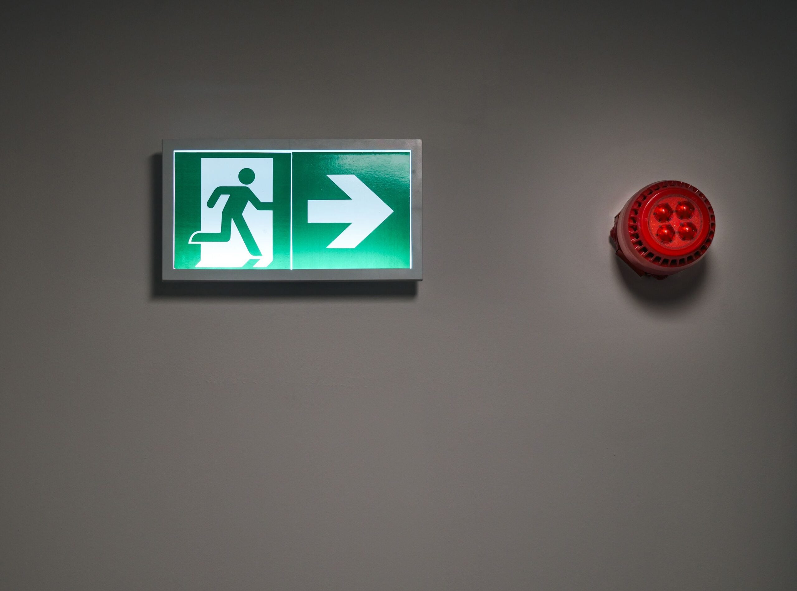 Emergency exit sign and fire alarm illustrating the importance of testing a business backup and disaster recovery plan.
